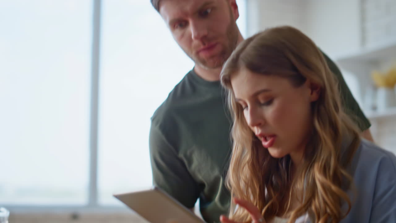 Dłonie małżonków szukające przepisu w kuchni z bliska. Para przegląda tablet