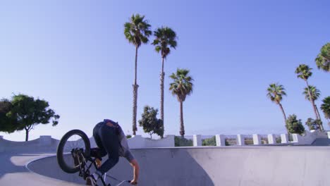 un ciclista de bmx hace un salto y monta la pared en un skatepark