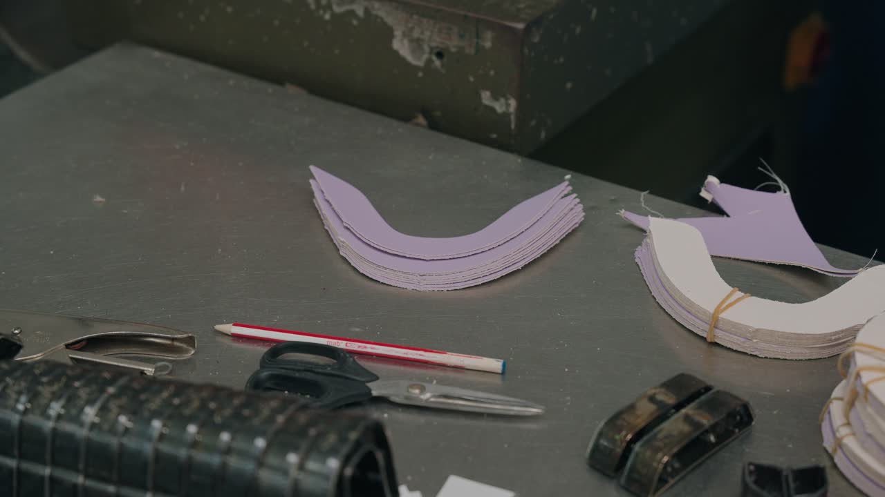 Primer plano de piezas de cuero y herramientas en un taller de zapatería