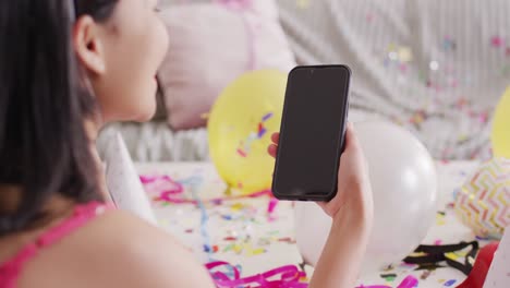video of smiling biracial woman dressed in pink dress using smartphone with blank screen