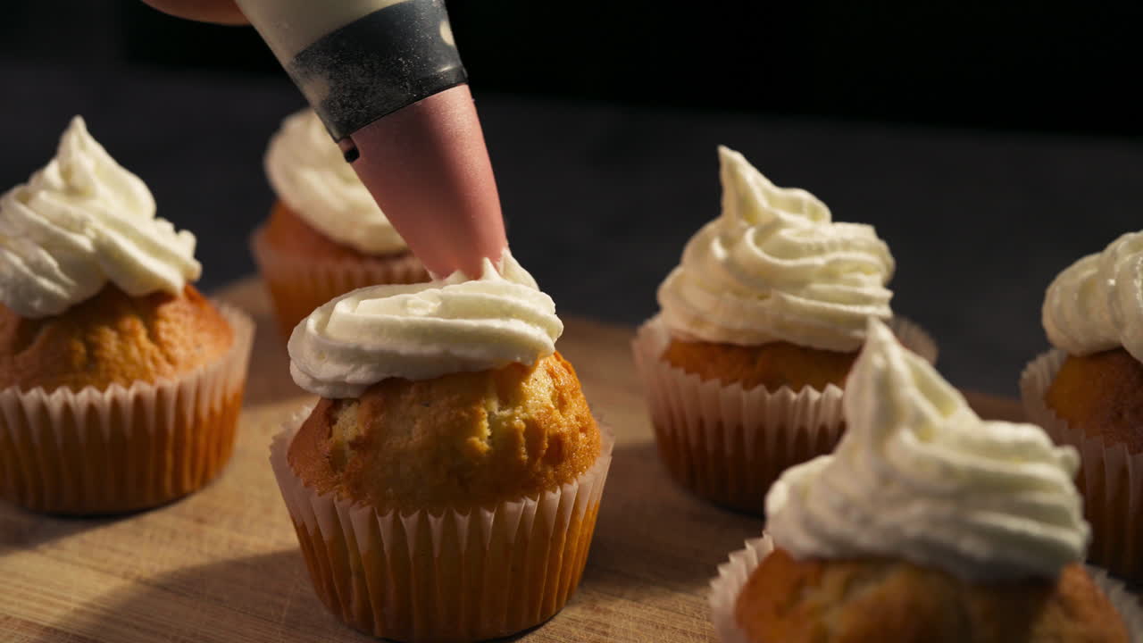 Simple classic frosting design swirl applied to cupcakes during the decorating process, slow motion closeup