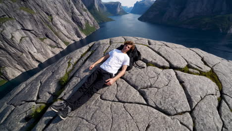 man lying on a fjord cliff edge