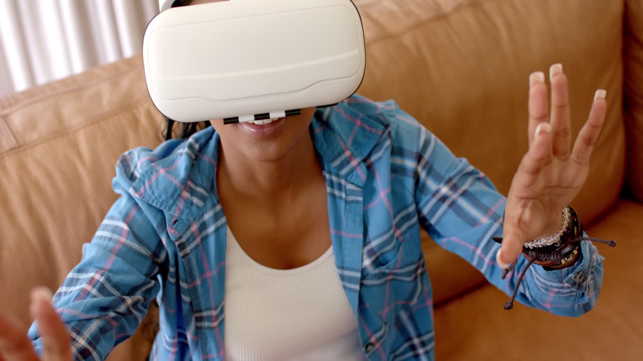 joven afroamericana con auriculares de realidad virtual, extendiendo la mano