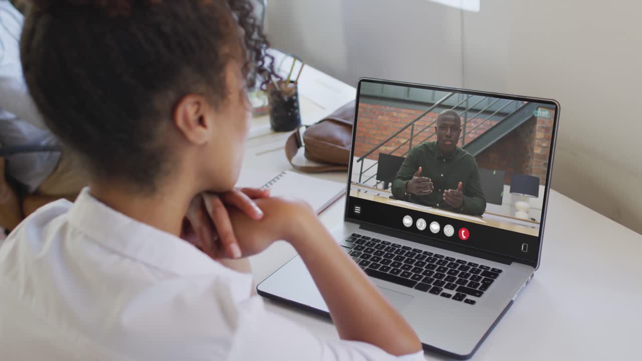 mujer afroamericana usando una computadora portátil para una llamada de video, con un colega de negocios en la pantalla