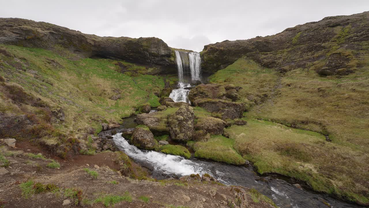 agua que fluye a lo largo de un arroyo alimentado por una cascada en islandia
