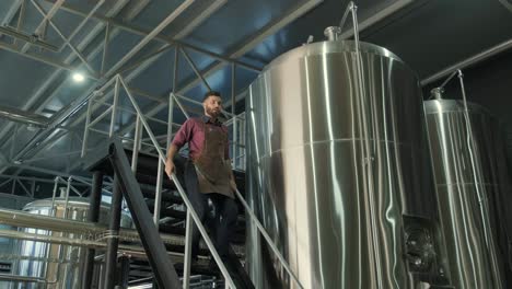 young male brewer works at a modern brewery