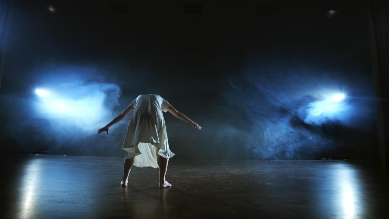mujer con vestido blanco en el escenario con humo bailando ballet moderno.