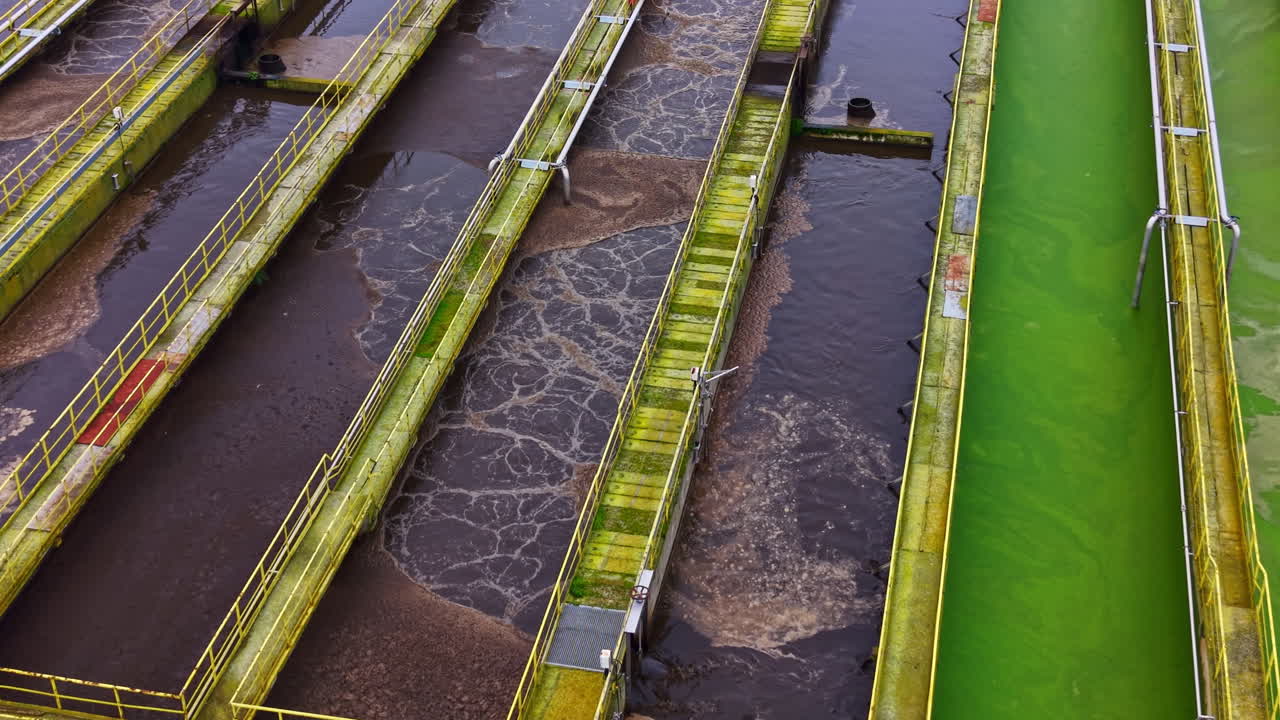 Wastewater treatment process takes place in large open tanks at a facility located in an industrial area during daylight hours