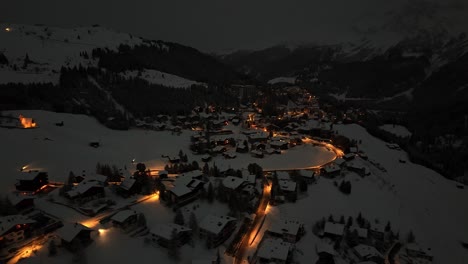 Toma-Aérea-De-Arriba-Hacia-Abajo-De-La-Famosa-Ciudad-Turística-De-Suiza-Llamada-Arosa,-Iluminación-Nocturna-Durante-La-Temporada-De-Invierno