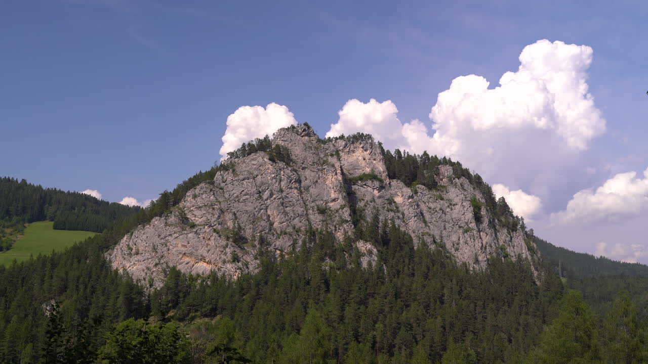 alta montaña rocosa en la naturaleza con hermosa formación de nubes y bosque
