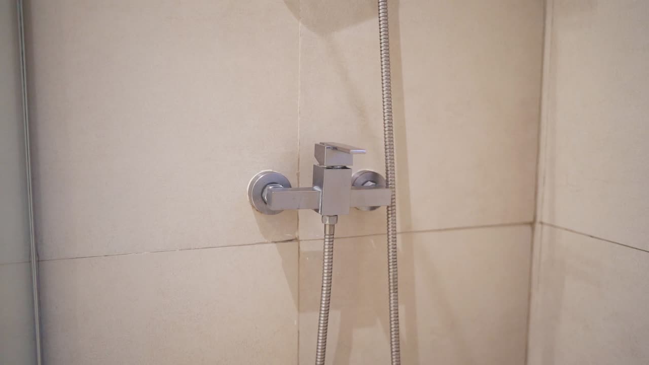 Close up of a modern shower fixture in a hotel bathroom, showcasing minimalist design and clean lines, reflecting a contemporary and sophisticated style