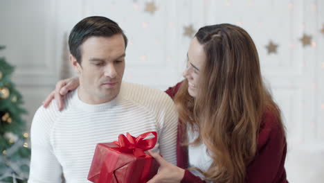 serious man working computer in christmas holiday. smiling woman presenting gift