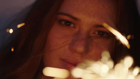 close up sparklers portrait of beautiful caucasian woman celebrating new years eve enjoying independence day celebration on beach at sunset