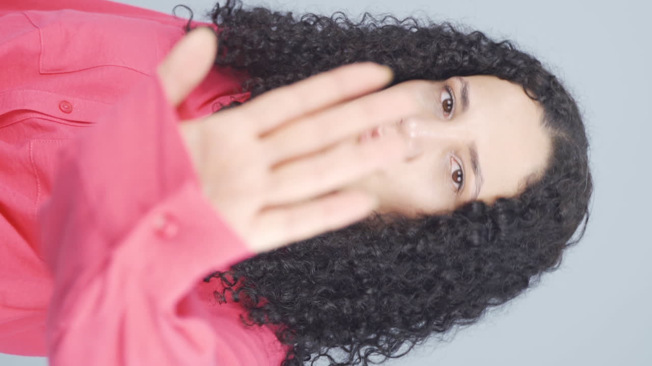 video vertical de una mujer joven haciendo una señal de alto para la cámara.