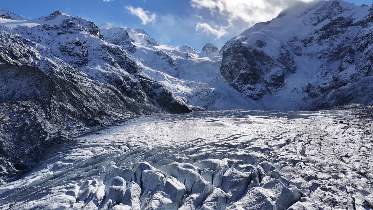 A detailed aerial view of the Morteratsch Glacier in Kanton Graubünden, Schweiz. The crevassed ice descends from the massive Bernina Alps, showcasing its immense size and dramatic texture