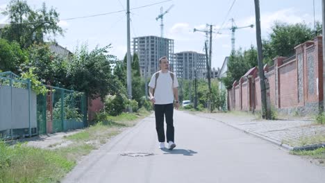 young man walking with guitar on street near forest