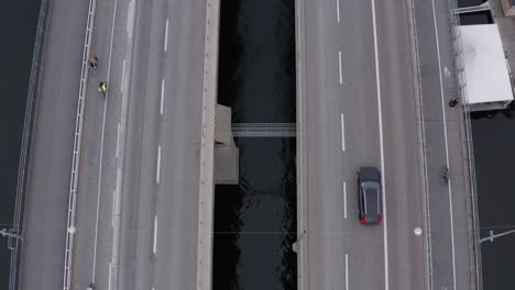 drone top-down view of pedestrians, bikers and traffic passing on liljeholmsbron towards liljeholmen and hornstull, söder, stockholm