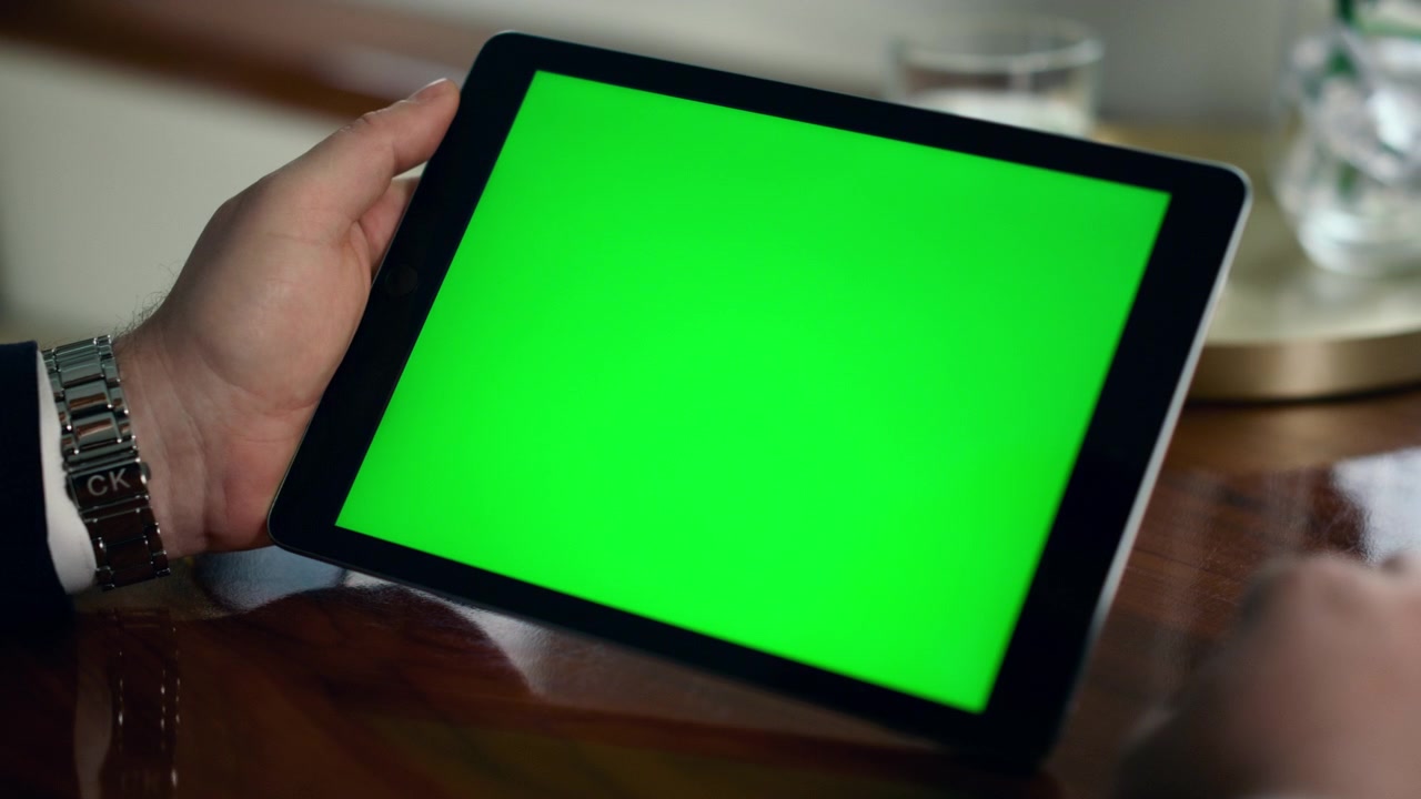 Nærbillede af mockup tabletcomputer i mands hænder. Forretningsmand holder tablet med grøn skærm.