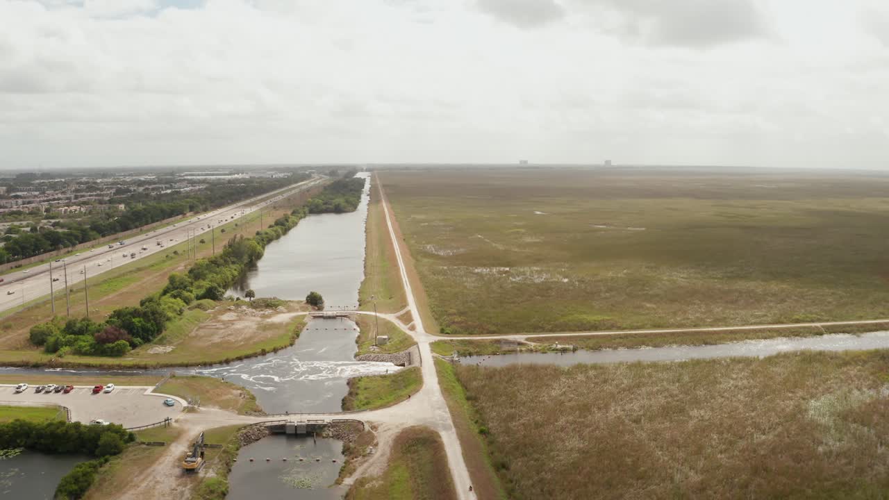 Drone shot of the Sawgrass in the Florida Everglades, close to Sawgrass next to the Levee. Moving Forward, with Sawgrass Expressway and Neighborhoods on the left