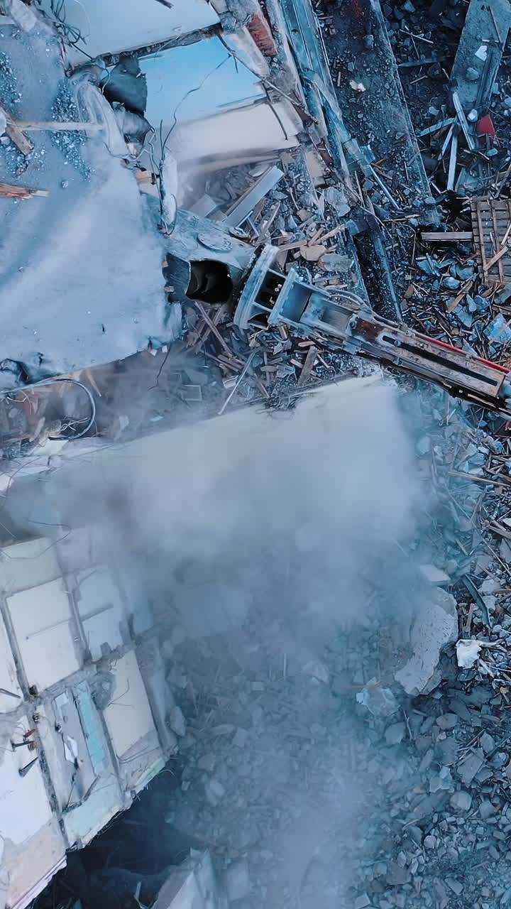 Hydraulic machinery working to get rid of the rubbish in a demolition site. High reach demolition excavator.View from above. Vertical video