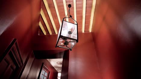 slow rotating shot of a clear antique light hanging in a red-walled room