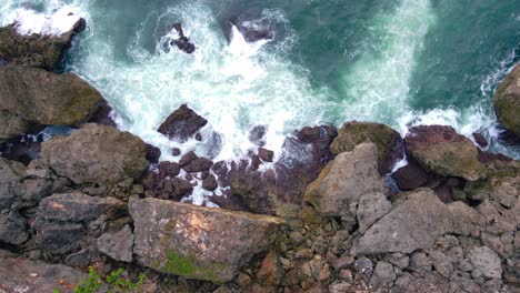 Overhead-drone-shot-of-rocky-beach-hits-by-big-sea-wave