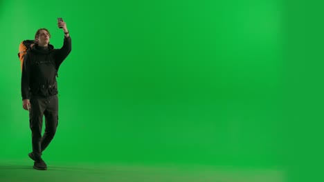 man with backpack using smartphone on green screen