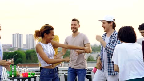 pretty mixed race girl is dancing with friends and laughing enjoying rooftop party. entertainment, partying outdoors and modern lifestyle concept.