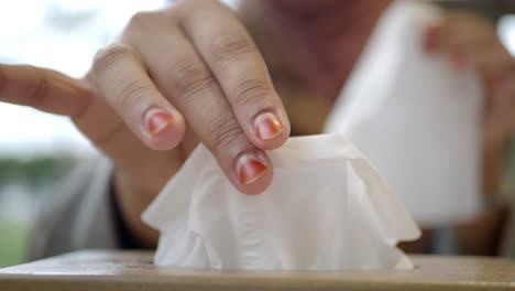 close up of a woman's hand reaching for a tissue from a box