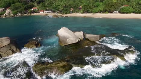 waves hitting rocks pan left to right sandy beach palm tree background