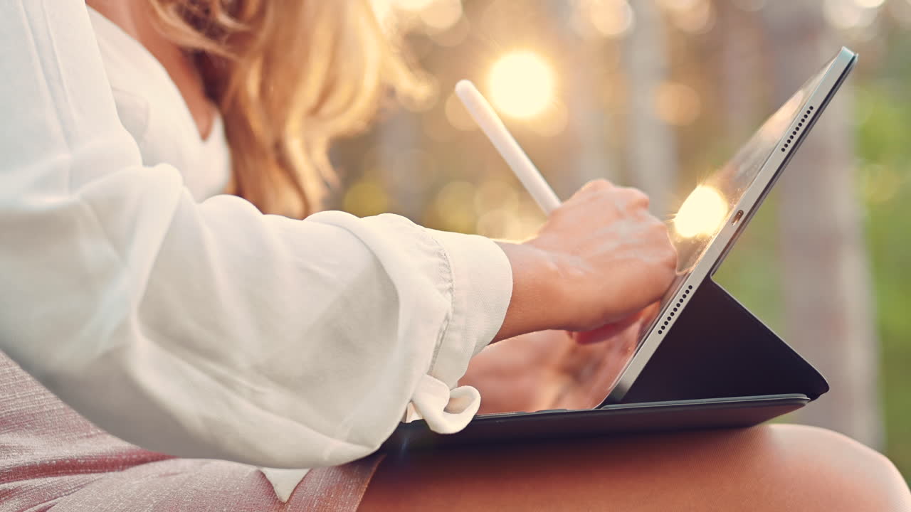 Woman sketching on a tablet with a stylus pen in the park