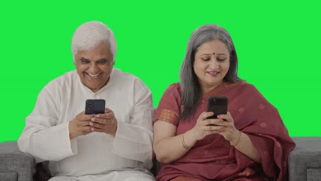 Happy-Old-Indian-couple-busy-in-their-phones-Green-screen