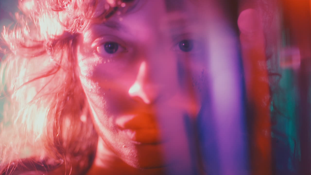 Portrait of Beautiful Girl with Glitter on Face in Multicolored Lighting