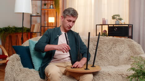 young man fixes wooden table at home with confident hands calm focused expression enjoying handywork
