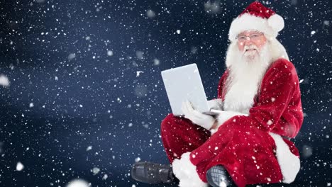 Santa-clause-sitting-in-front-of-his-laptop-combined-with-falling-snow