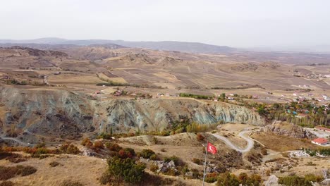 Drohnenschuss-In-Den-Orangefarbenen-Und-Besonders-Blauen-Rocky-Mountains-Der-Türkei,-Die-Türkische-Nationalflagge-Hängt-Im-Starken-Wind