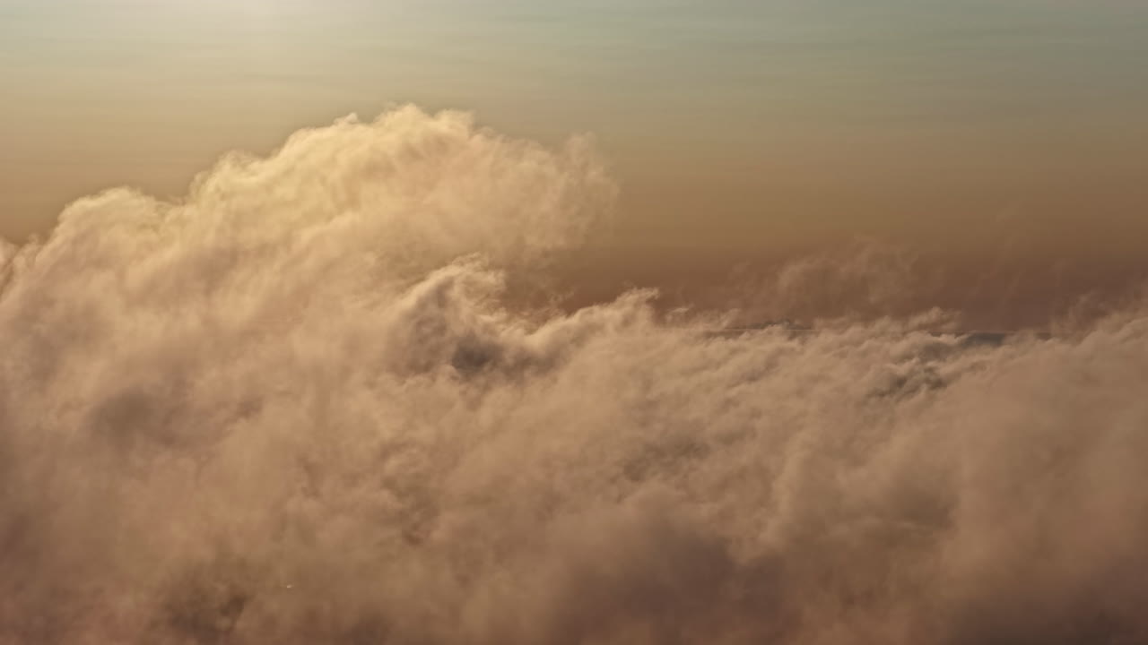 Thick orange clouds illuminated by sunset light in the sky from above