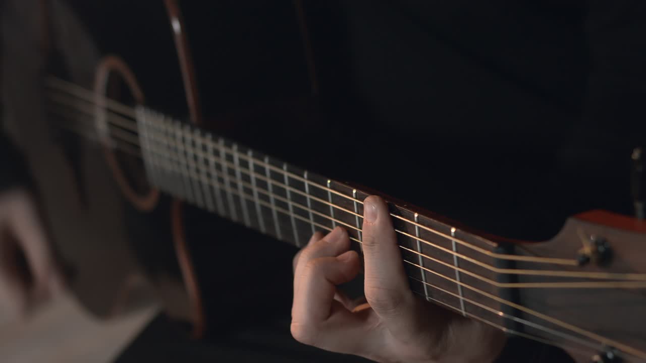 un hombre con una sudadera negra toca la guitarra acústica