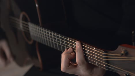 man in a black sweatshirt plays the acoustic guitar