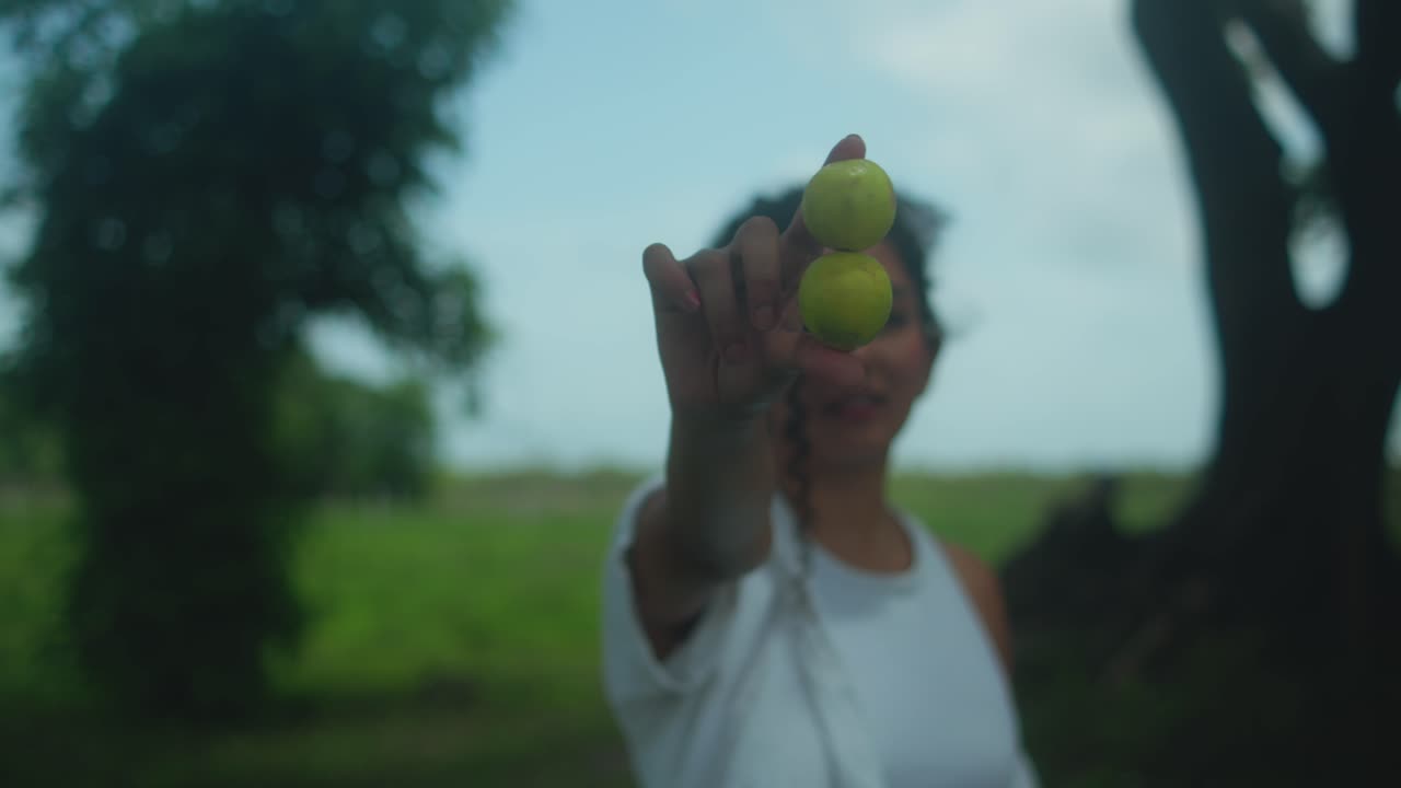 Una donna in piedi in una foresta tiene due mele tra le dita, unendo la bellezza naturale a uno stile di vita sano e consapevole. Ottimo per progetti a tema benessere, cibo e natura.