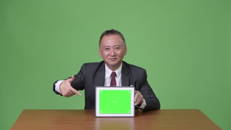 디지털 태블릿을 보여주는 성숙한 일본 사업가