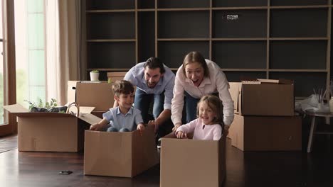una pareja feliz juega con niños pequeños en su nueva casa.