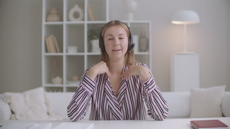 young-female-business-training-is-greeting-audience-and-starting-webinar-looking-at-camera-portrait-in-room