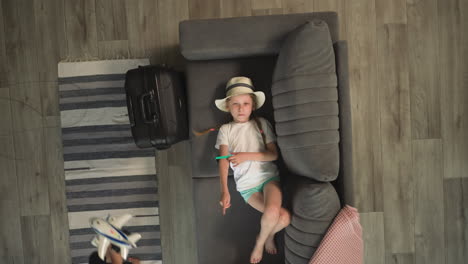 niña pequeña juega con gafas de sol acostada en el sofá en la habitación