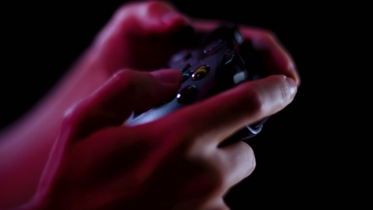 Playing video games in a darkened room with a black background close up on a controller buttons playing slowly
