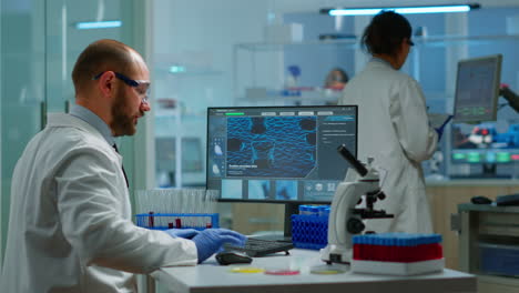 man biologist checking dna informations typing on pc