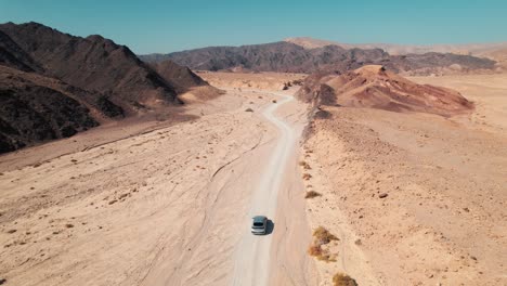 a car driving in the desert in a path through the mountains in israel