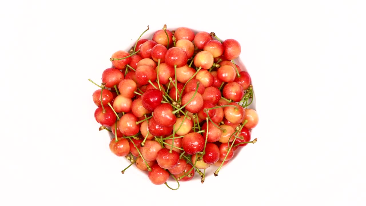 Ripe juicy yellow sweet cherries on plate. Side view. Clockwise rotation. Loop motion.