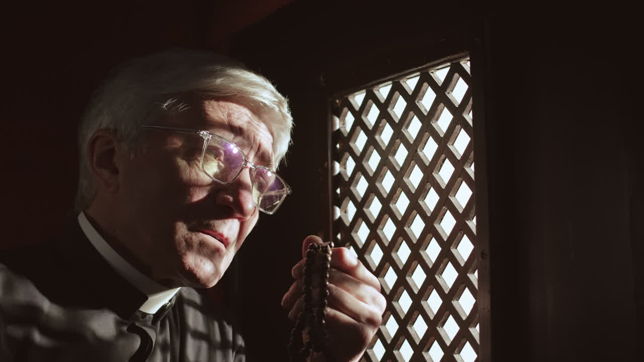 Aged Priest Sitting in Confessional Booth