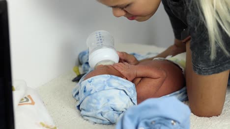 anonymous mother feeding newborn baby wrapped on soft blanket